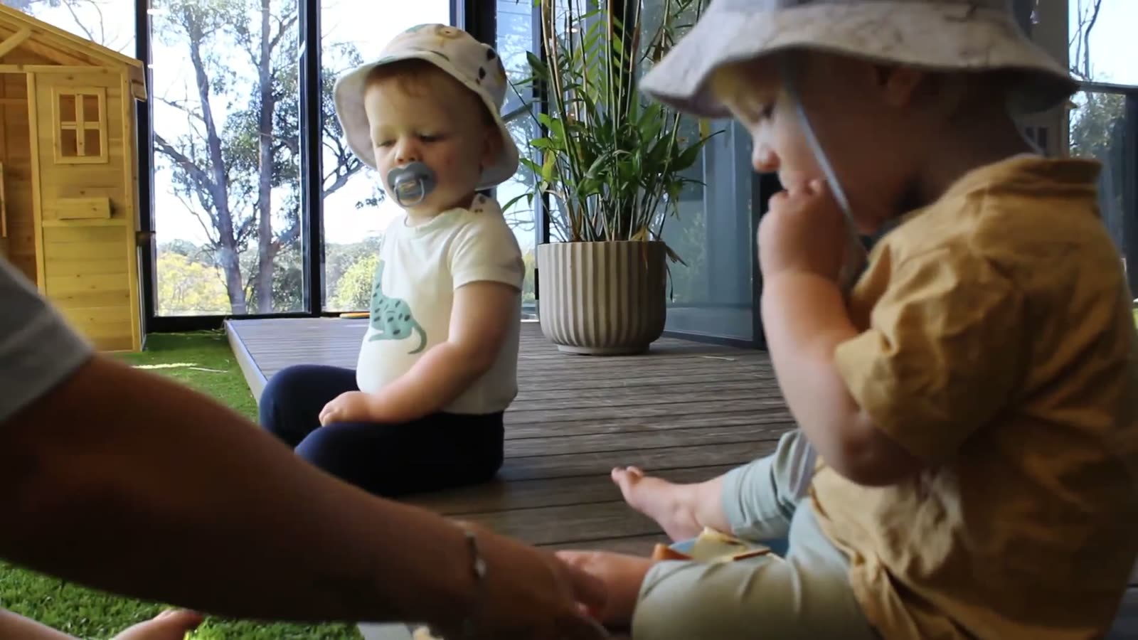 Two toddlers sitting together on the deck